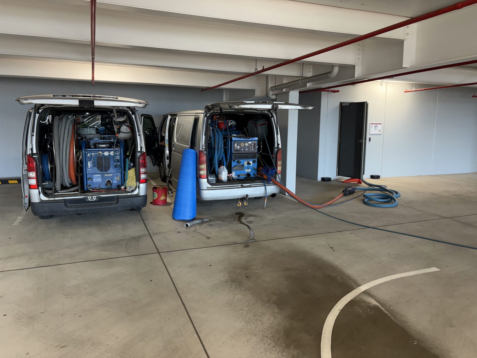 Two Pro Carpet and Tile vans with hoses out on a commercial job